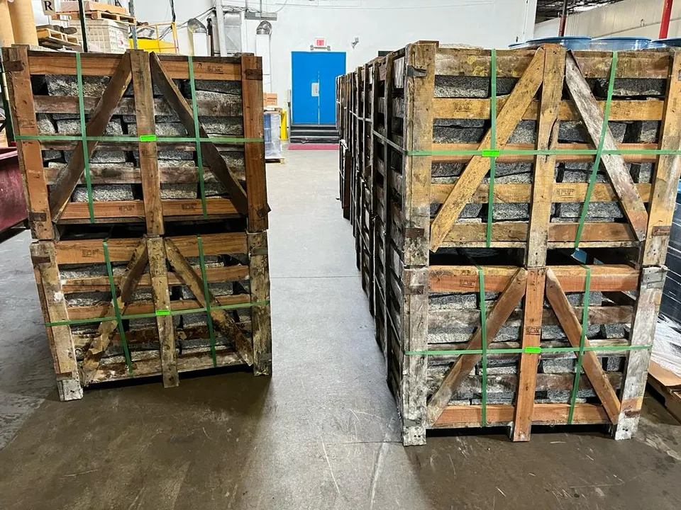 Photograph of two stacks of closed wooden crates of granite, strapped with banding
