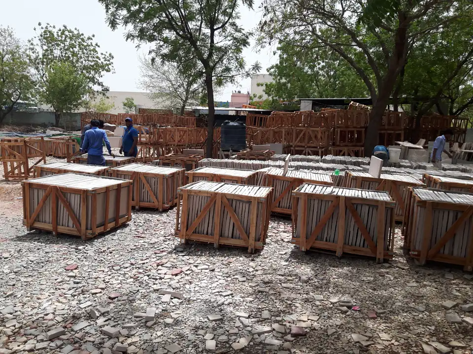 Photograph of rows of wooden crates of cut stone in a stockyard in India